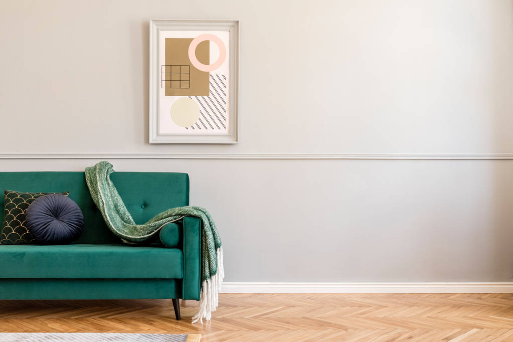 Stylový a elegantní obývací pokoj interiéru se zelenou sametovou pohovkou, moderními polštáři, přikrývkou a elegantními doplňky. Na šedivé stěně se zformoval rám obrazů. Luxusní Domácí výzdoba.  - Fotografie, Obrázek