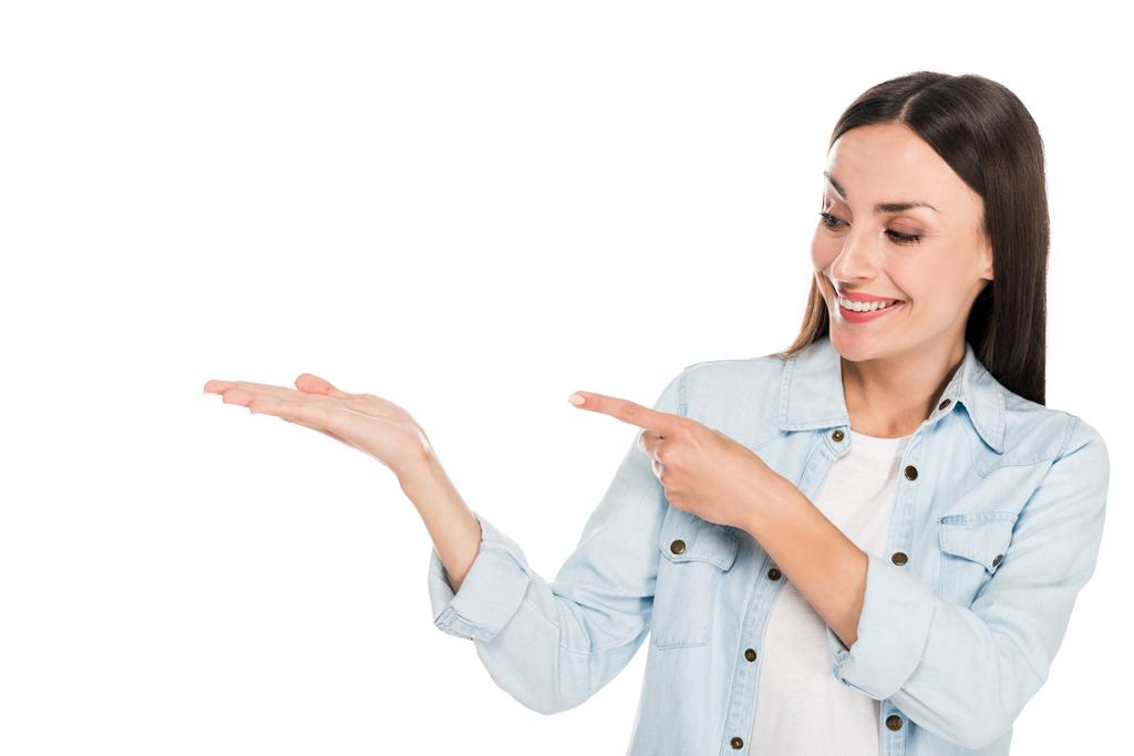 glückliche brünette Frau zeigt mit dem Finger zur Seite isoliert auf weiß - Foto, Bild