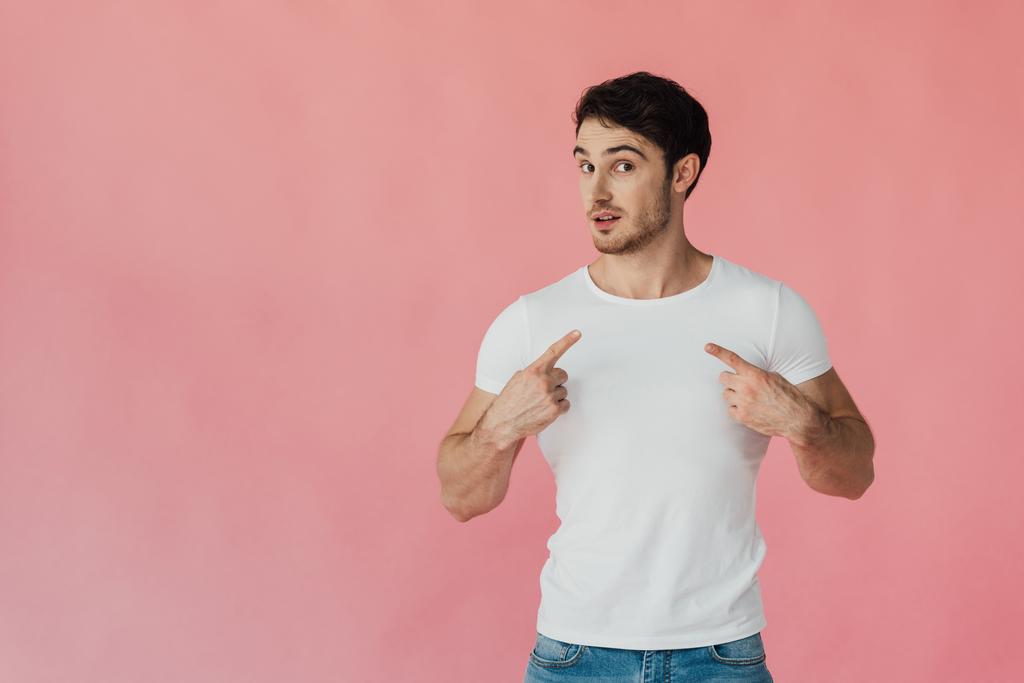 мускулистый мужчина в белой футболке, указывающий пальцами на себя, изолированный на розовом
 - Фото, изображение
