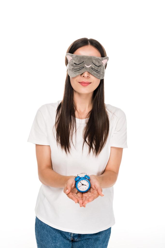 brünette junge Frau in Katze schlafenden Augenmaske hält Spielzeug Wecker isoliert auf weiß - Foto, Bild