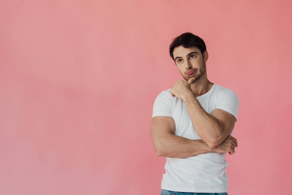 Nachdenklicher muskulöser Mann im weißen T-Shirt vereinzelt auf rosa - Foto, Bild