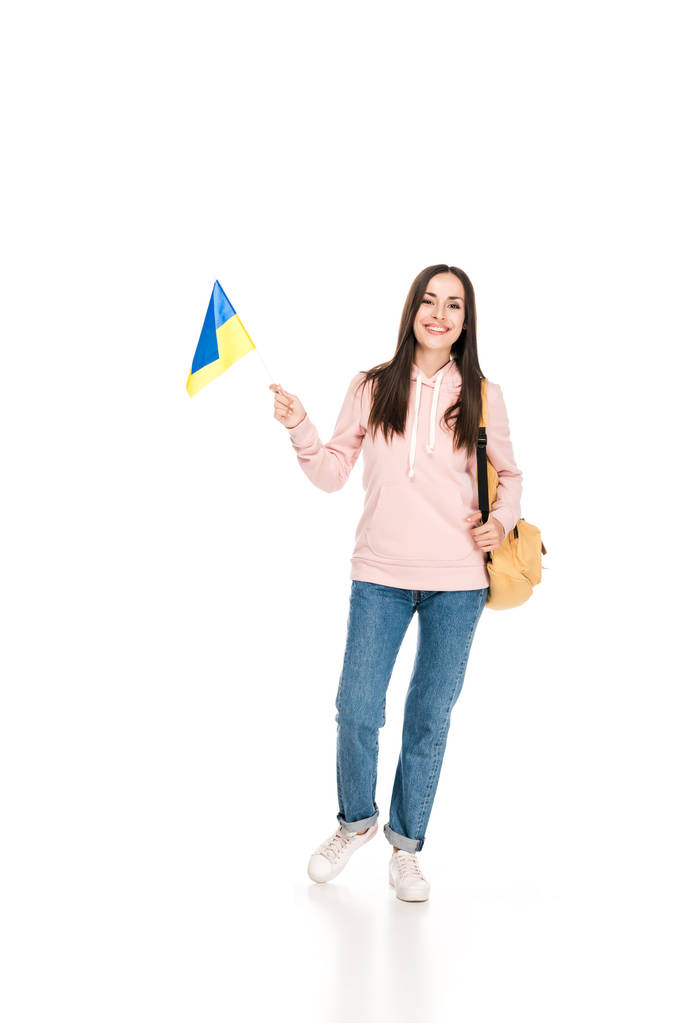 полный вид улыбающейся брюнетки с рюкзаком с украинским флагом, изолированным на белом
 - Фото, изображение