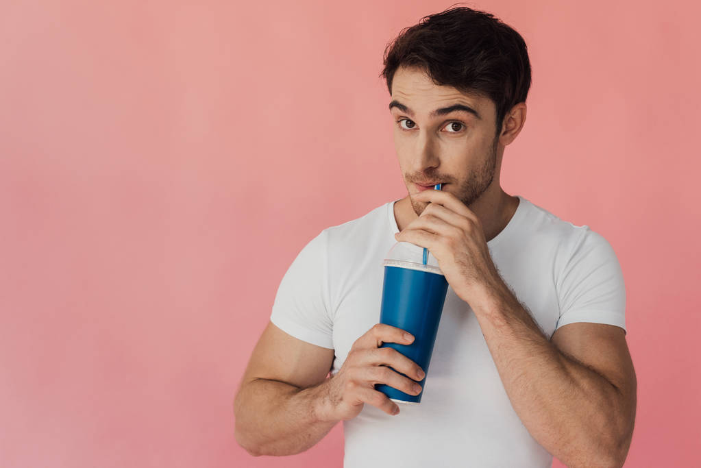 muscular man in white t-shirt drinking beverage isolated on pink - Photo, Image
