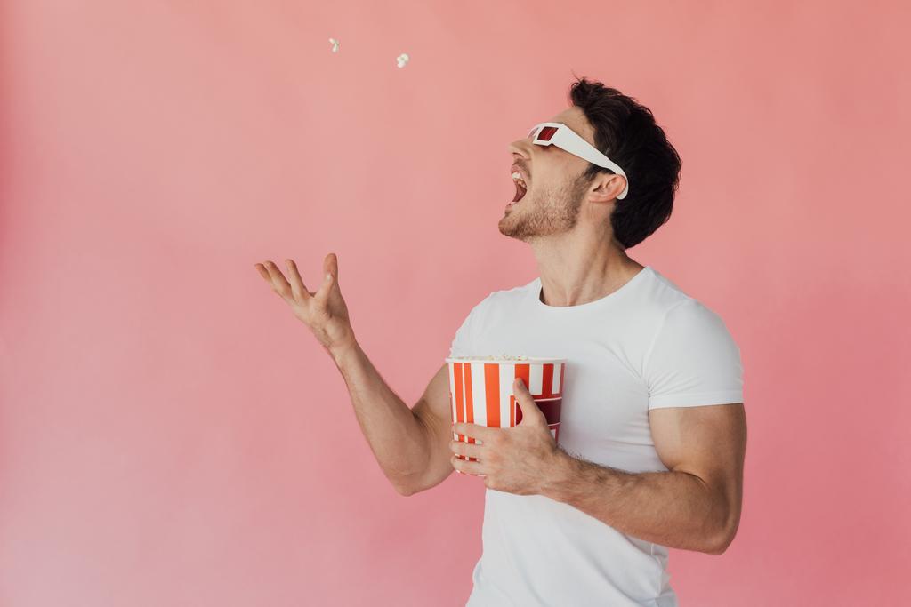 muscular man in 3d glasses throwing up and eating popcorn isolated on pink - Photo, Image