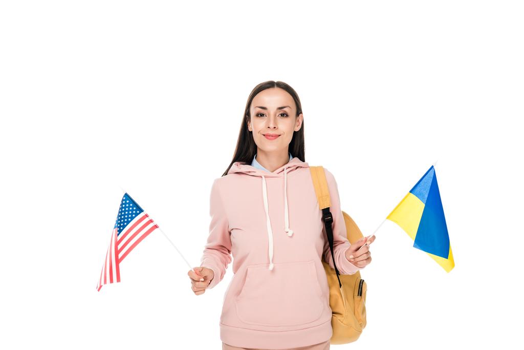 улыбающийся студент с рюкзаком, держащий украинский и американский флаги изолированные на белом
 - Фото, изображение