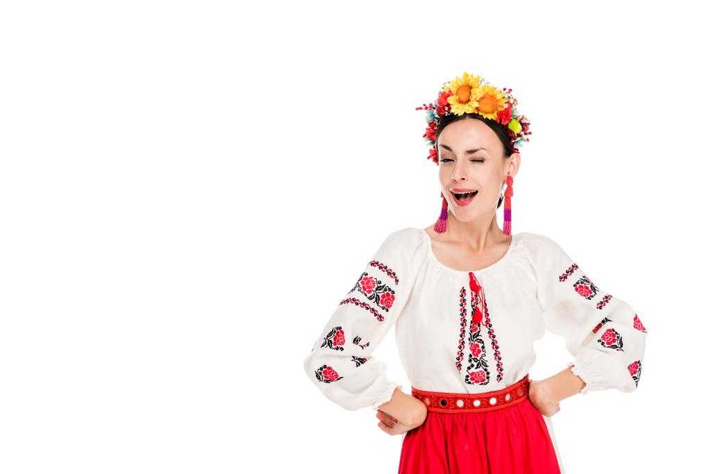 brunette young woman in national Ukrainian costume with hands on hips winking isolated on white - Photo, Image