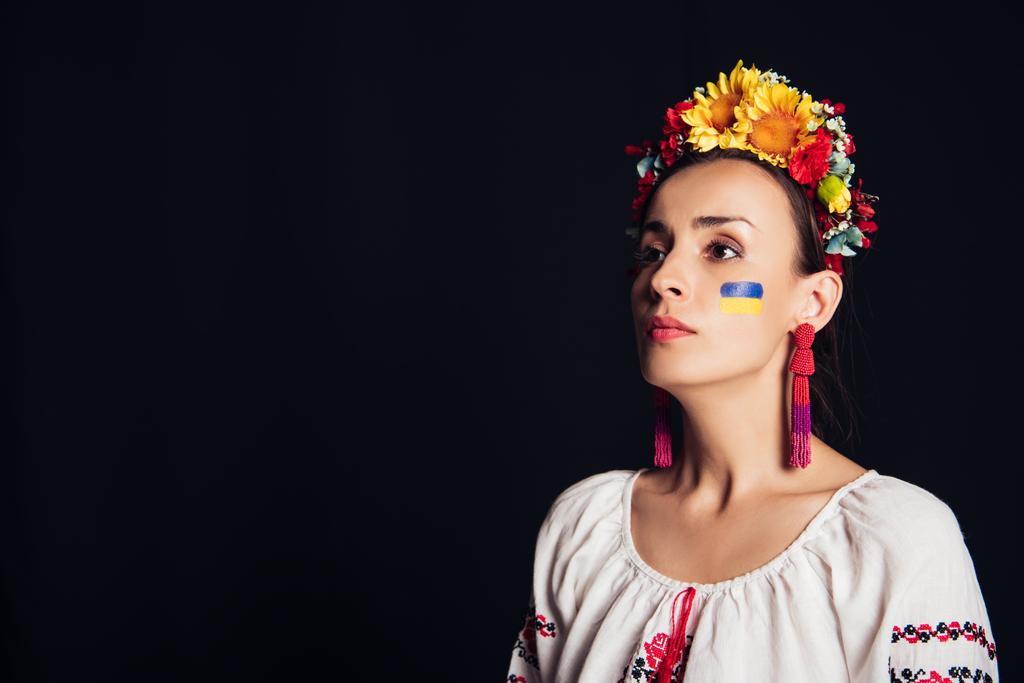 Brunette fiatal nő a nemzeti ukrán ruha-és virágos koszorú elnéz elszigetelt fekete - Fotó, kép