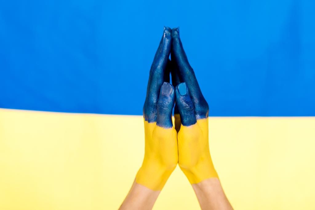 vista recortada de manos de oración pintadas en el fondo de la bandera de Ucrania
 - Foto, Imagen