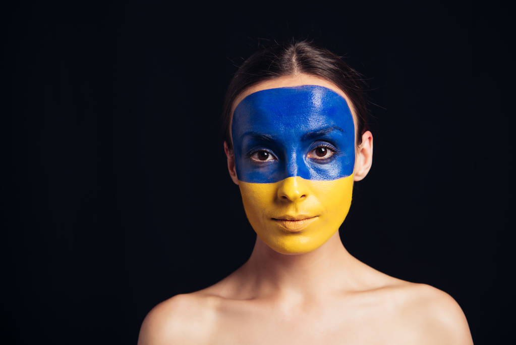 jovem mulher nua com bandeira ucraniana pintada na pele olhando para a câmera isolada no preto
 - Foto, Imagem