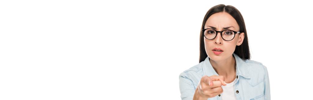 wütendes brünettes Mädchen mit Brille in Jeansjacke, das mit dem Finger auf Kamera zeigt, isoliert auf weißer, panoramischer Aufnahme - Foto, Bild