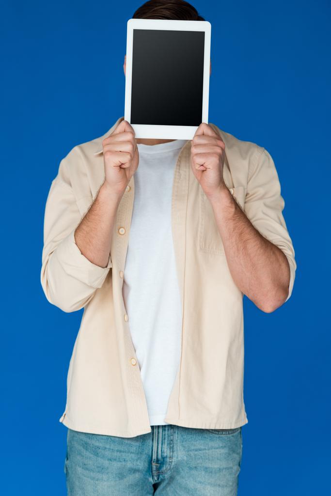 青で隔離された空白の画面を持つデジタルタブレットを保持するシャツの若い男の正面図 - 写真・画像