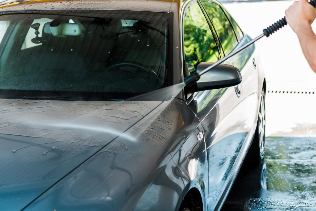 bijgesneden beeld van man wassen grijs auto buiten  - Foto, afbeelding