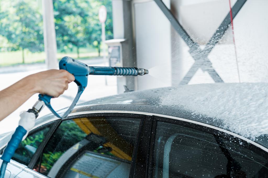 cropped view of man holding pressure washer with foam near car  - Photo, Image