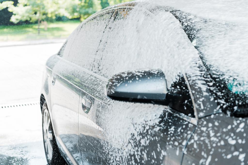 wit schuim op moderne auto in carwash  - Foto, afbeelding