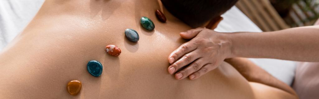plano panorámico de masajista y hombre sin camisa con piedras en la espalda
 - Foto, imagen