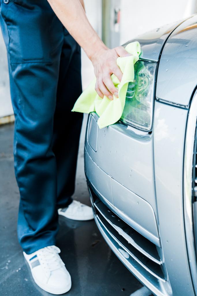 abgeschnittene Ansicht der Autowäsche mit grünem Lappen beim Reinigen der Autoscheinwerfer - Foto, Bild