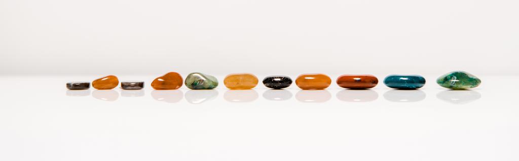 plano panorámico de piedras semipreciosas de colores sobre una superficie blanca aislada en gris
 - Foto, imagen