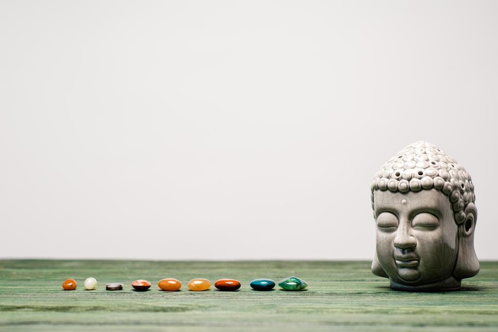 Buddha-Statuette und bunte Halbedelsteine auf hölzerner Oberfläche isoliert auf grau - Foto, Bild