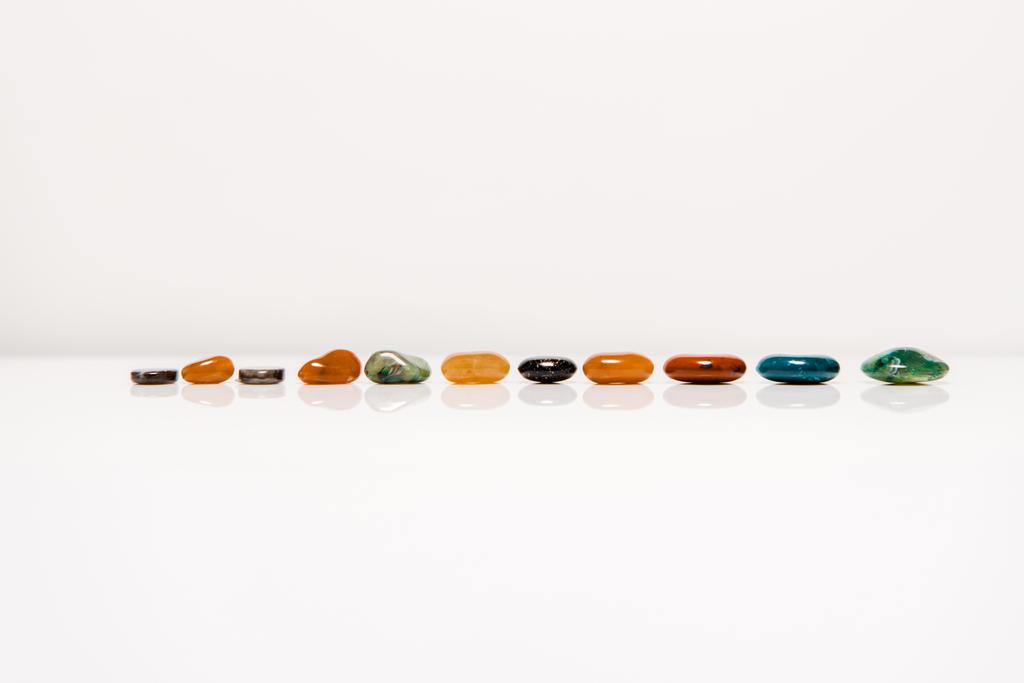 colorful semiprecious stones on white surface isolated on grey - Photo, Image