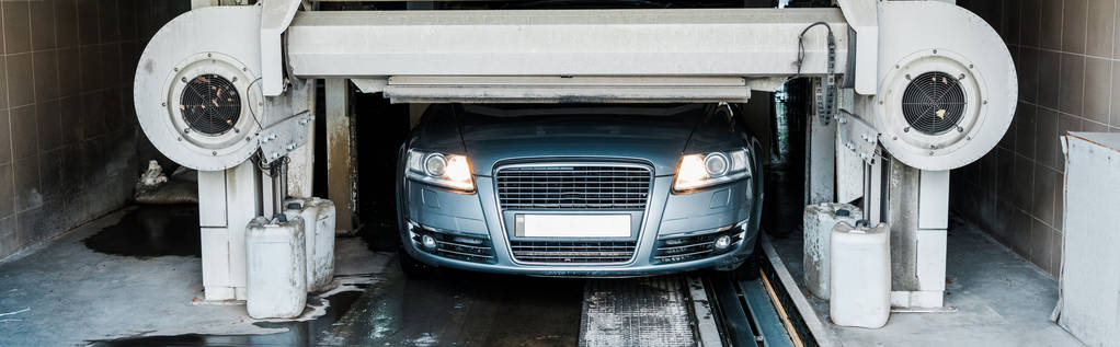 panoramatický záběr šedého automobilu s reflektory auta zářícím do mytí aut  - Fotografie, Obrázek