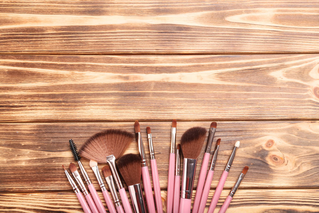 Conjunto de pinceles de maquillaje sobre mesa de madera marrón
 - Foto, Imagen