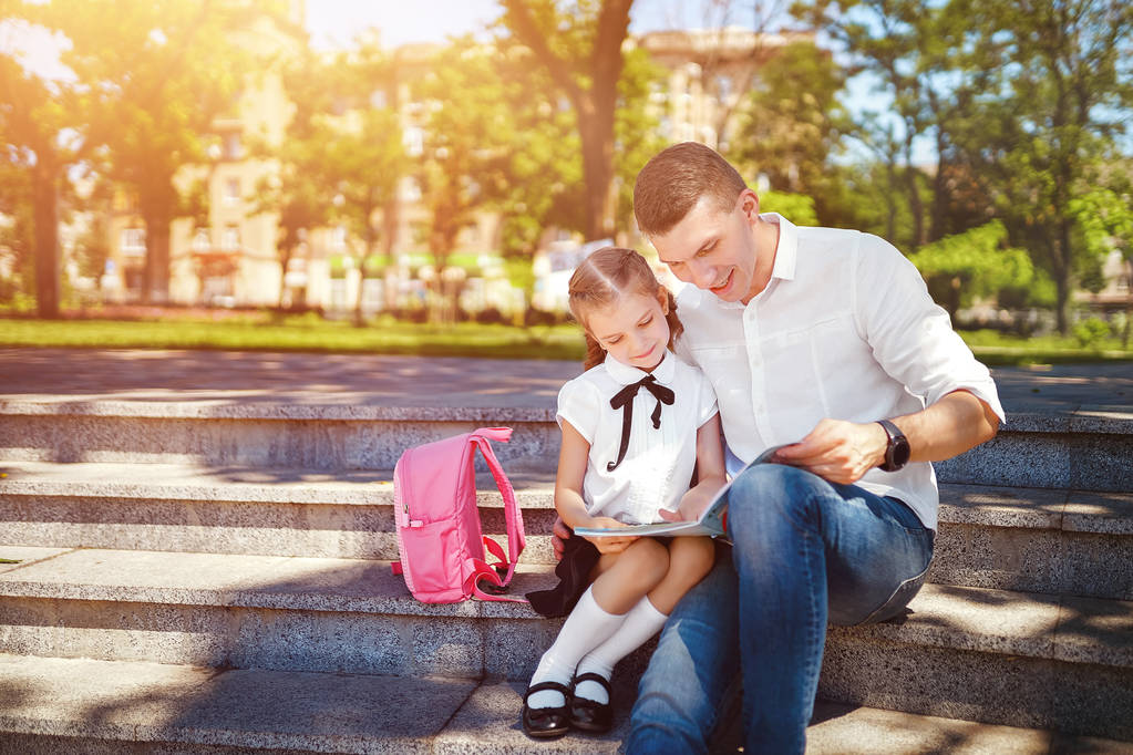 Otec a dcerka sedí na schodech a čtou si knížky, studijní hodiny. Rodičovství a dětský koncept - Fotografie, Obrázek