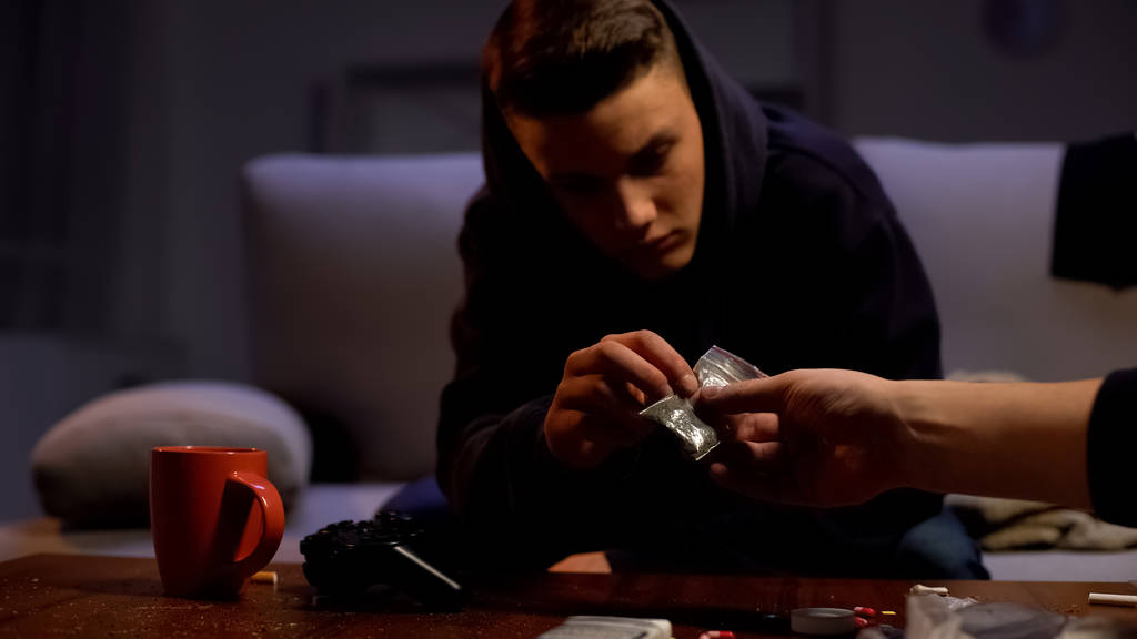 Rivenditore che dà pacchetto marijuana per adolescente maschio, problema di tossicodipendenza
 - Foto, immagini