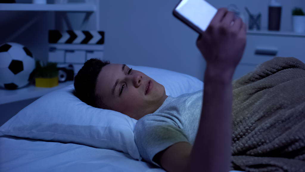 Teenager watching adult content on smartphone in the evening, puberty age - Photo, Image