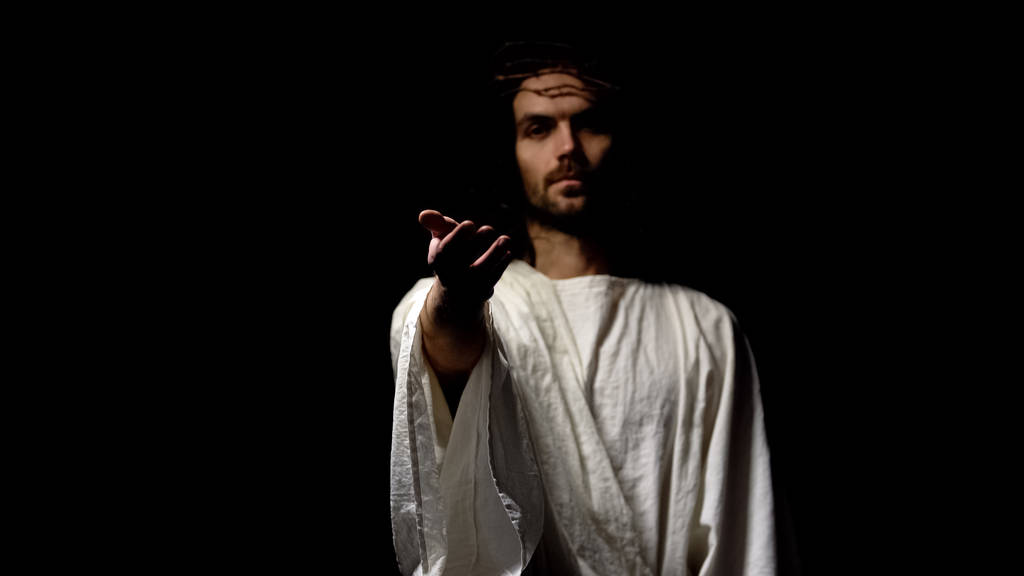 Jesus em coroa de espinhos e roupão dando a mão, pedindo crença e bondade
 - Foto, Imagem