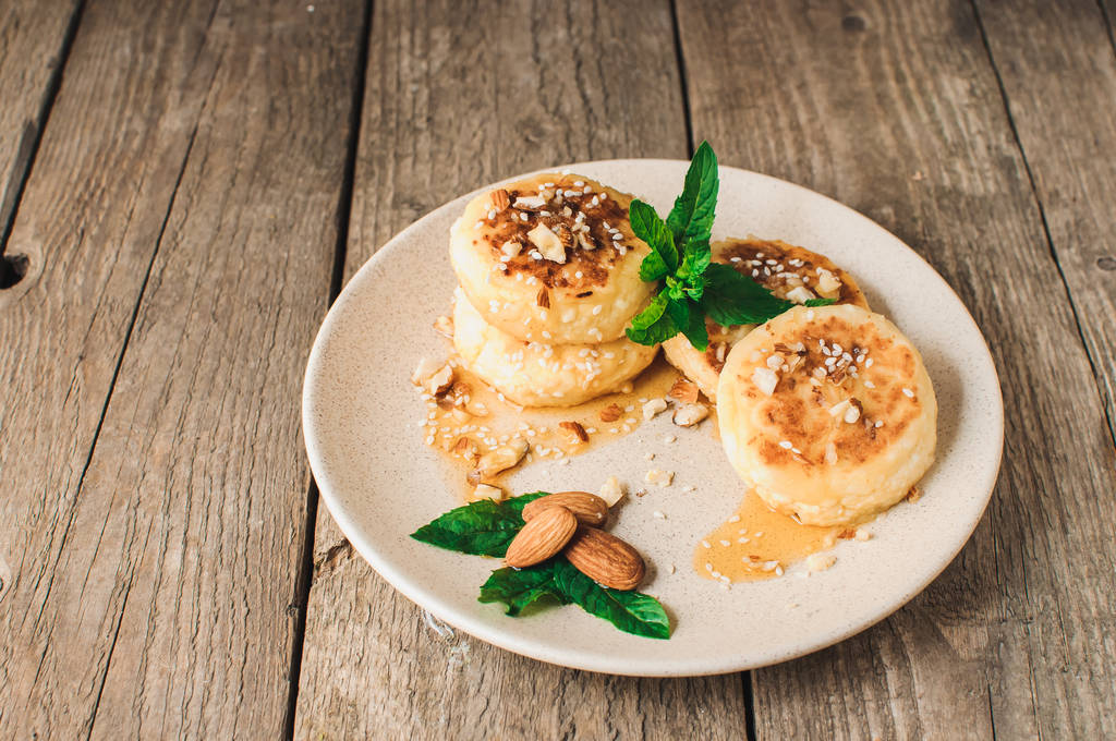 おいしい朝食 - カッテージチーズパンケーキ、チーズケーキ、アーモンド、ミント、メープルシロップのベージュプレートのカッテージチーズパンケーキ。素朴なスタイルで木製のテーブルの上に便利なデザート。選択フォーカス. - 写真・画像