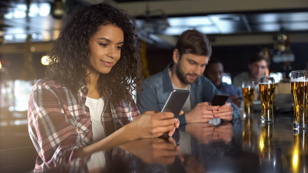 Multiracial people scrolling phones in pub instead of communication, addiction - Photo, Image