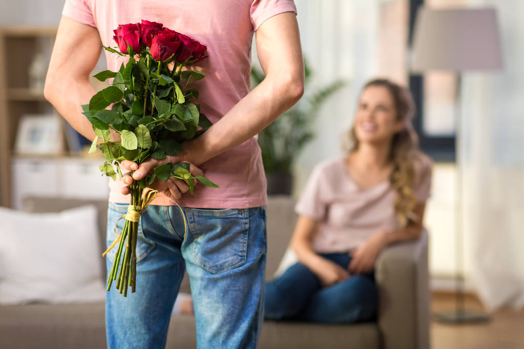 女性と彼の背中の後ろにバラの花束を持つ男 - 写真・画像