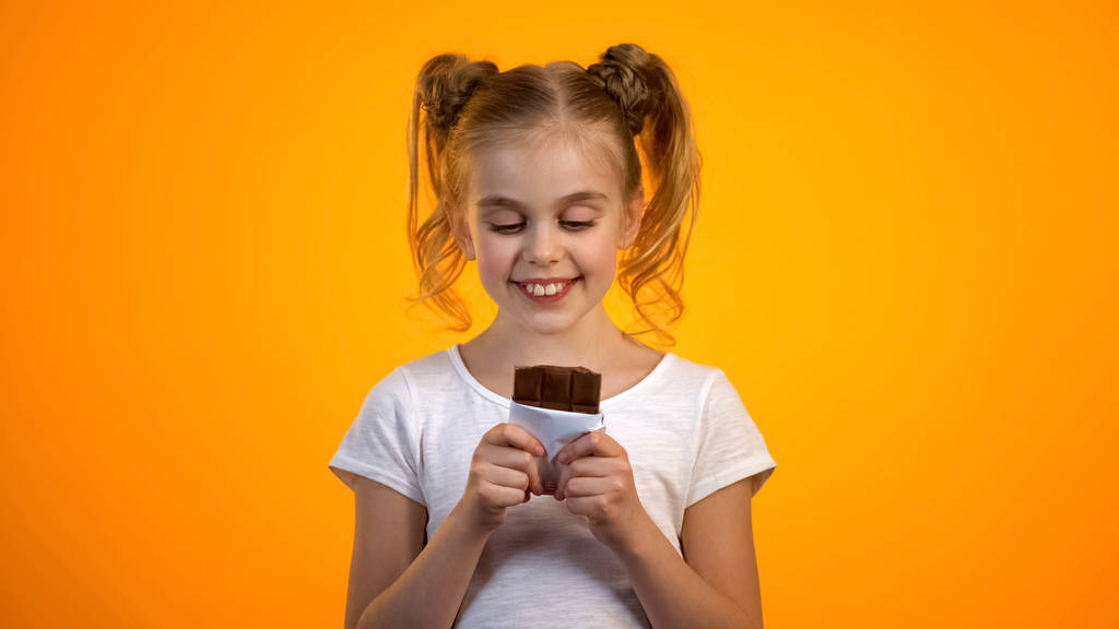 Happy preteen dziewczyna trzyma płytkę pysznej czekolady ciesząc się smakiem, emocje - Zdjęcie, obraz