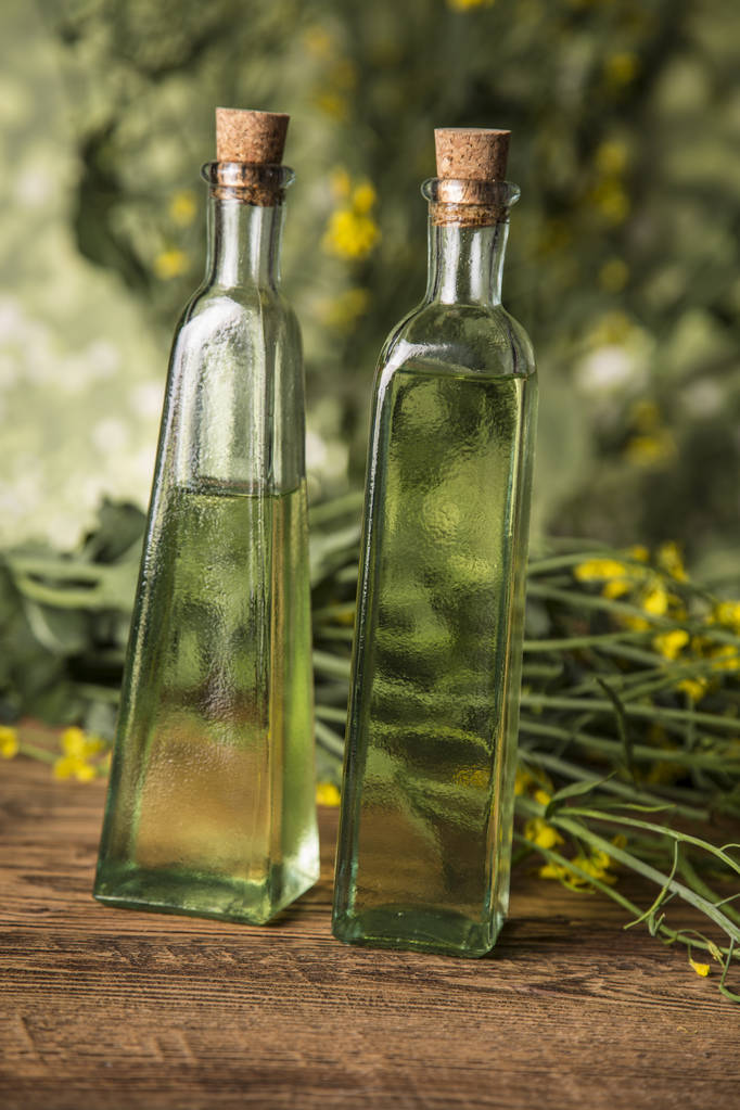 テーブルの上のボトルに菜種の花や菜種油 - 写真・画像
