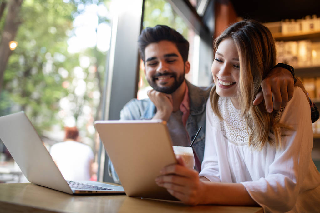 Jeune couple heureux travaille dans un café sur ordinateur portable et souriant
. - Photo, image