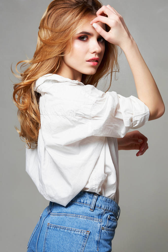 Мінімалістичний стиль міського одягу, макет для друкованого магазину. Дівчина в порожній білій футболці і джинсах позує на білу стіну
 - Фото, зображення