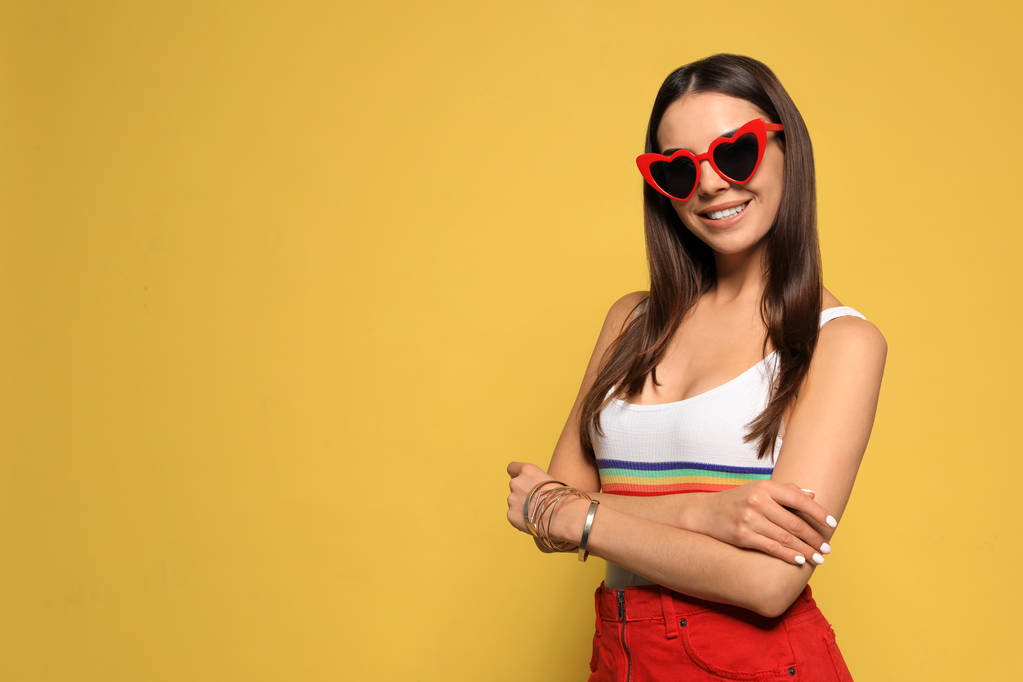 Portrait of beautiful young woman with heart shaped sunglasses on color background. Space for text - Photo, Image
