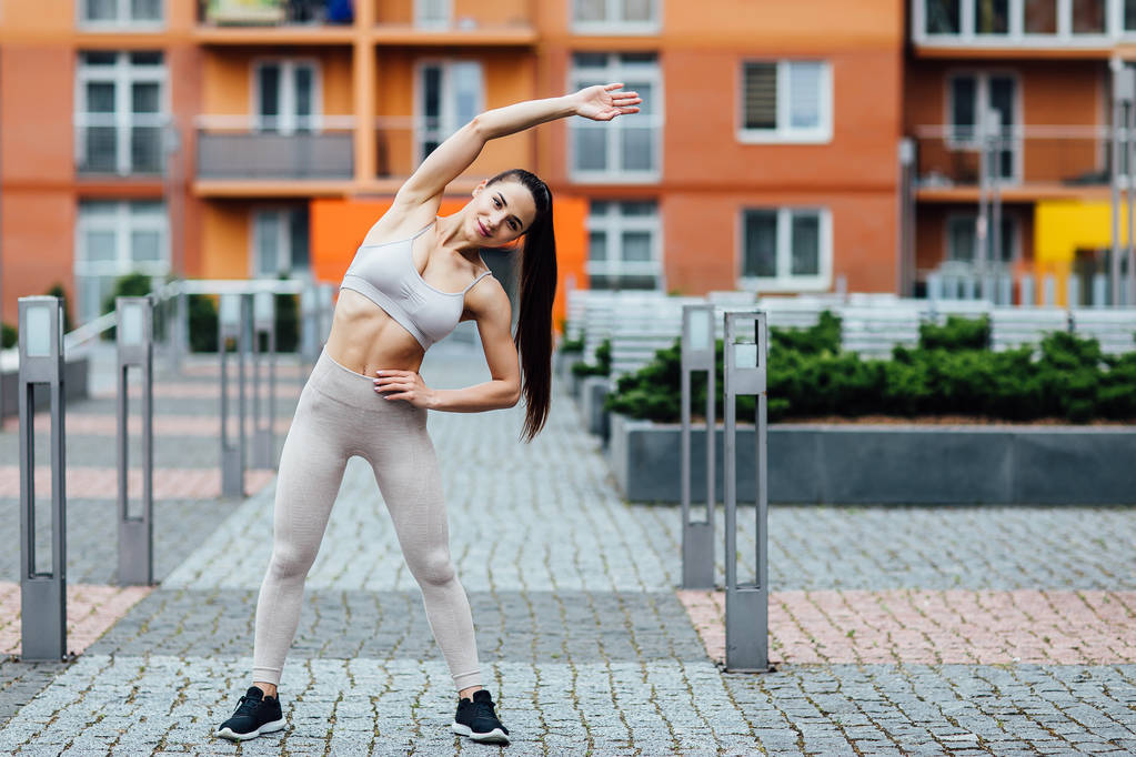 Schöne junge Frau bei Übungen im Freien. Herrliche Fitness weibliches Training hart. - Foto, Bild