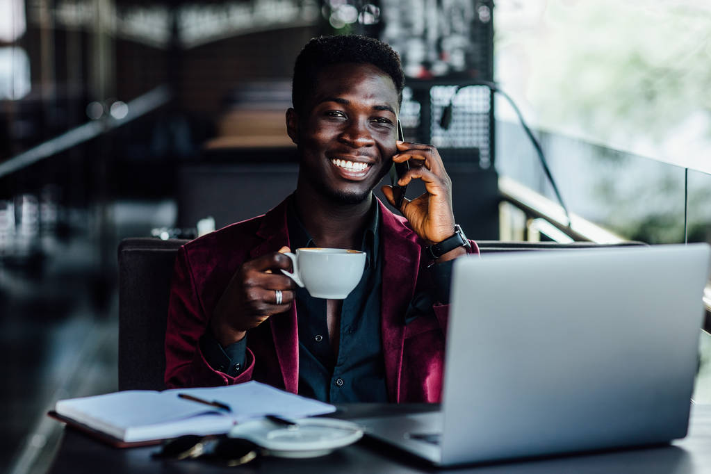 Komea malli, afrikkalainen nuori mies työskentelee kannettavan tietokoneen ulkopuolella terassi Euroopan kaupungin kahvilassa
. - Valokuva, kuva