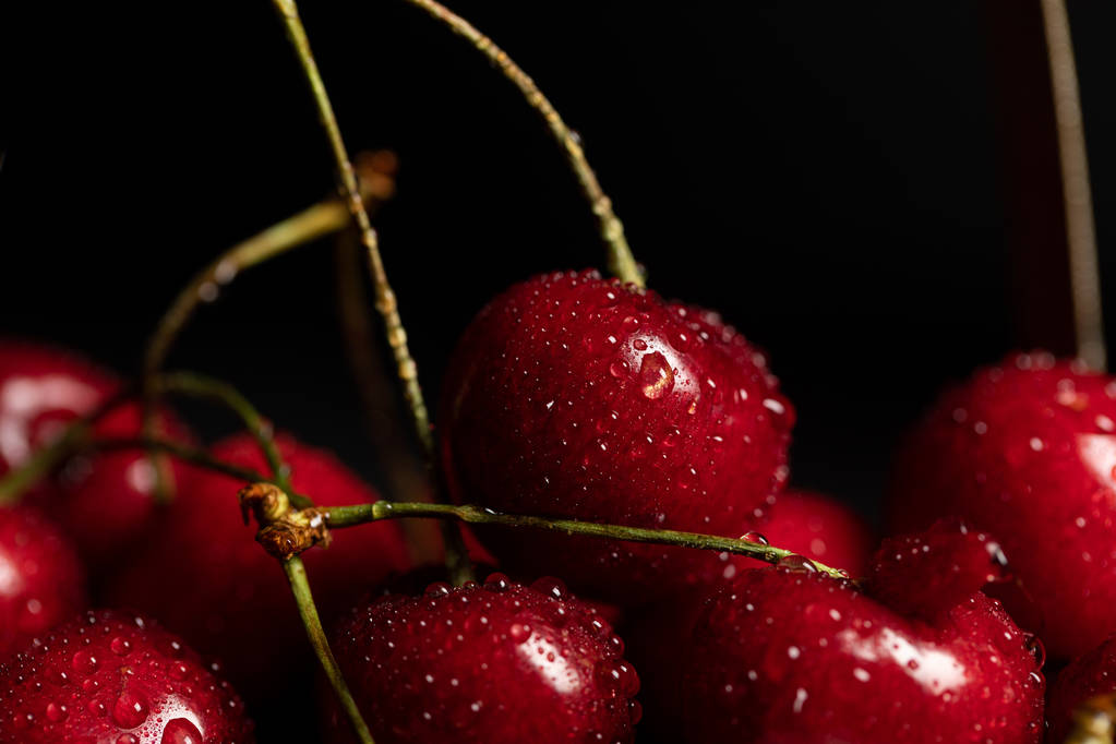 близкий вид на красные вкусные вишни с капли воды изолированы на черном
 - Фото, изображение