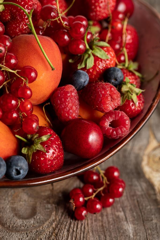 закрыть вид на спелые сезонные ягоды и абрикосы на деревянном столе
 - Фото, изображение