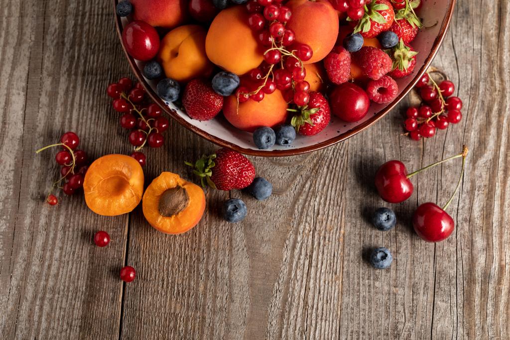 top view of ripe seasonal berries and apricots on plate on wooden table - Photo, Image