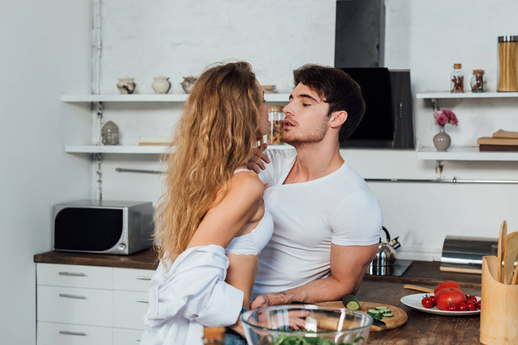 сексуальная пара, смотрящая друг на друга возле стола с овощами на кухне
 - Фото, изображение