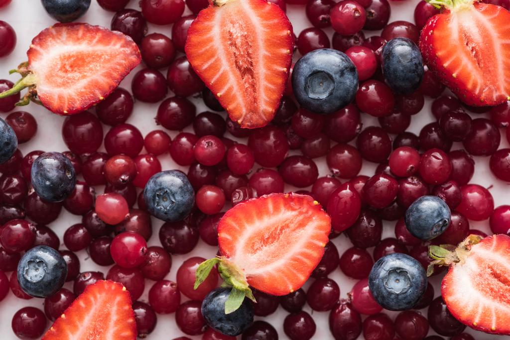 vue de dessus des canneberges rouges, fraîches et mûres, des fraises coupées et des bleuets entiers
  - Photo, image
