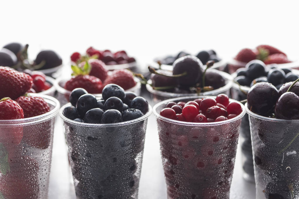 селективный фокус клюквы, клубники, черники и вишни в пластиковых чашках
  - Фото, изображение