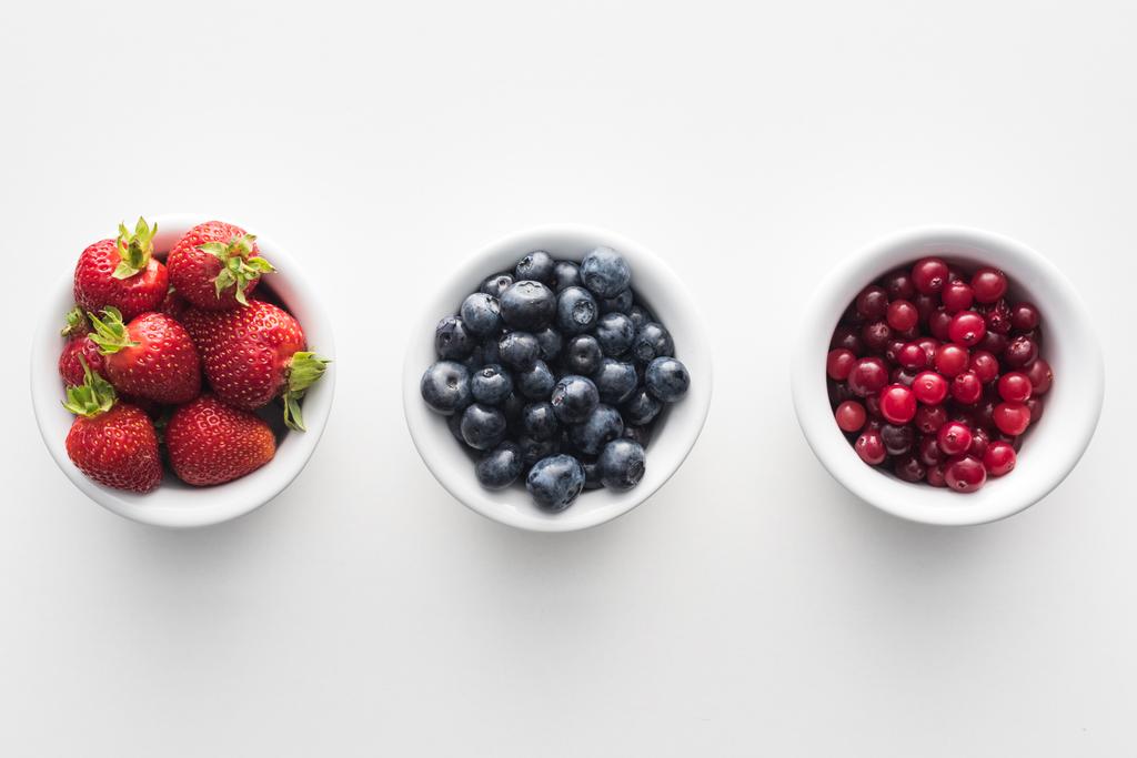 vista superior de arándanos y arándanos dulces, fresas en tazones blancos
  - Foto, Imagen