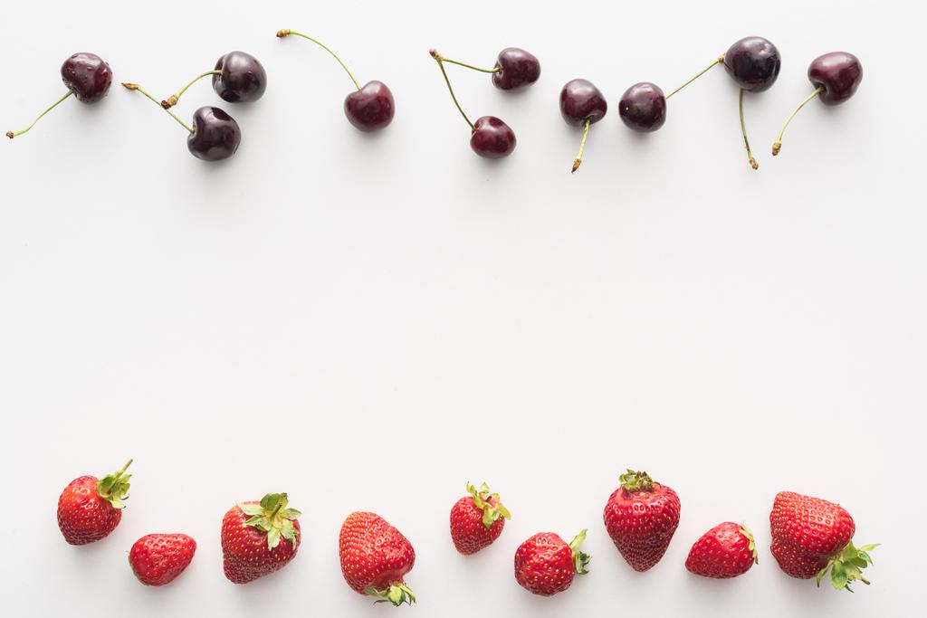 vista superior de cerezas dulces y frescas y fresas rojas sobre fondo blanco
  - Foto, imagen