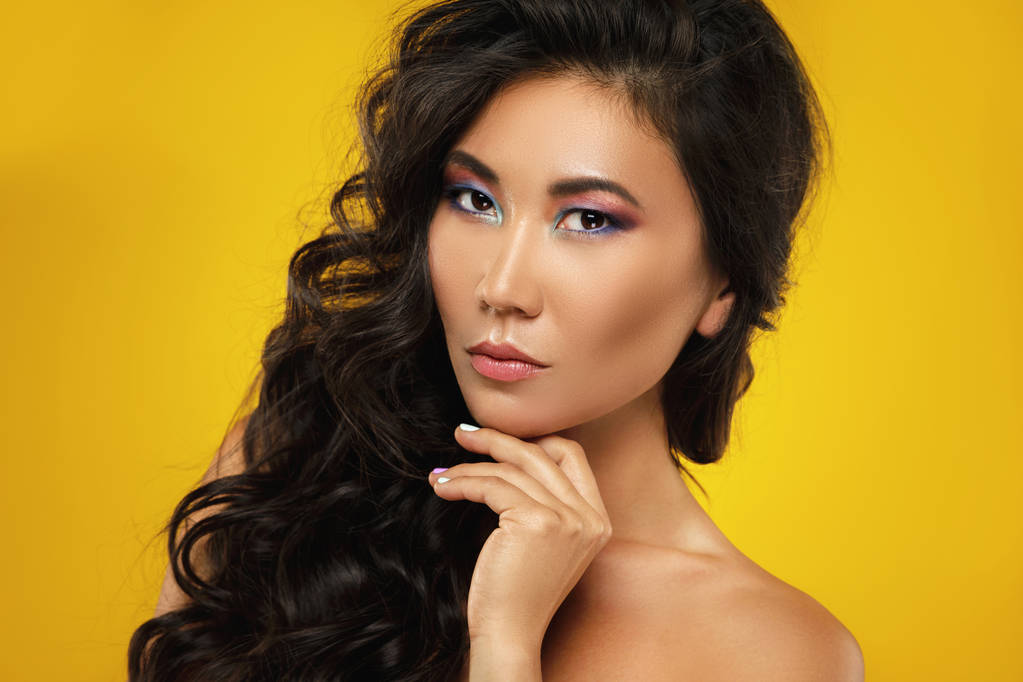 Mujer asiática con un hermoso pelo rizado y maquillaje en ba amarilla
 - Foto, Imagen
