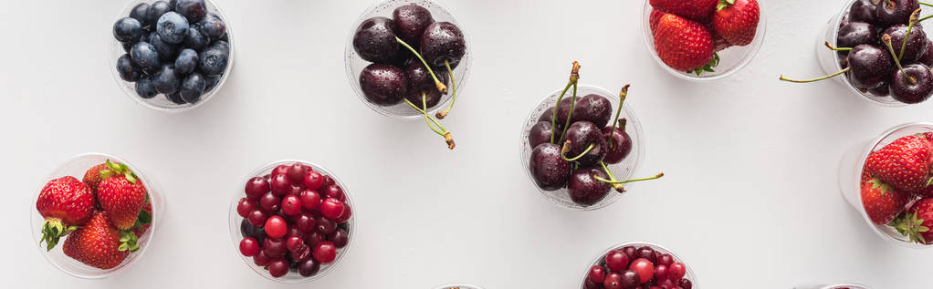 панорамный снимок свежей клубники, черники, вишни и клюквы в пластиковых чашках
  - Фото, изображение