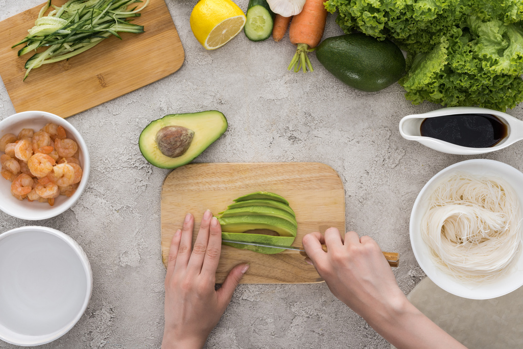 top view of woman cutting avocado with knife on cutting board  - Photo, Image